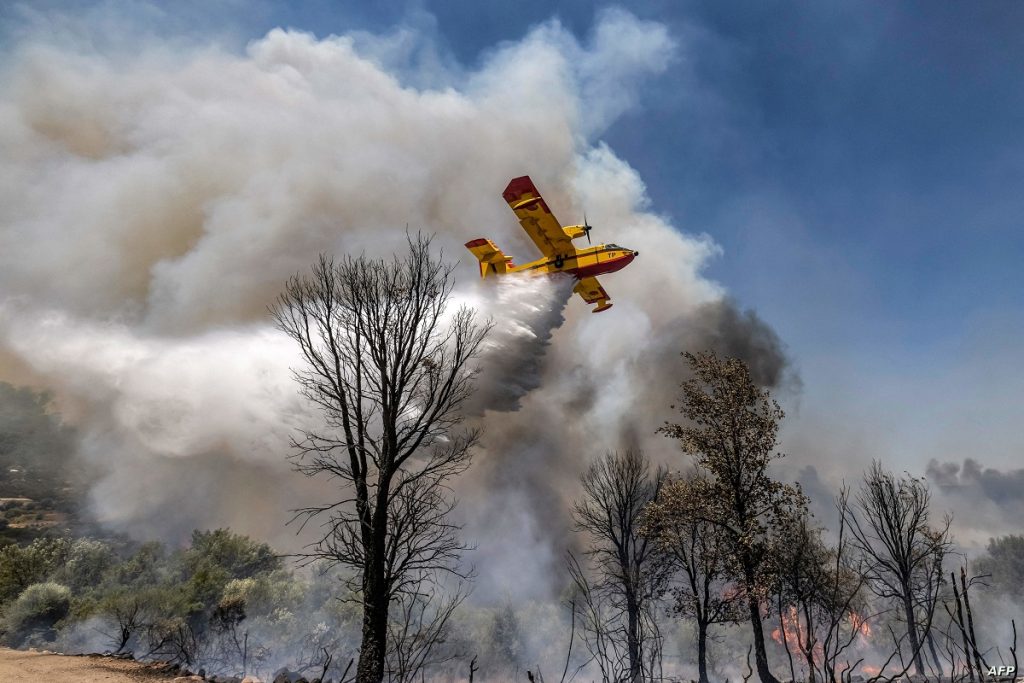 A Royal Moroccan Air Force Canadair CL-415 firefighting aircraft douses a wildfire with retardant spray to extinguish a wild forest fire raging near the Moroccan city of Ksar el-Kebir in the Larache region on July 14, 2022. (Photo by FADEL SENNA / AFP)