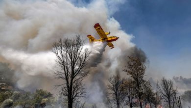 A Royal Moroccan Air Force Canadair CL-415 firefighting aircraft douses a wildfire with retardant spray to extinguish a wild forest fire raging near the Moroccan city of Ksar el-Kebir in the Larache region on July 14, 2022. (Photo by FADEL SENNA / AFP)